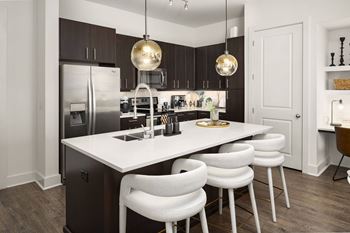 a kitchen with stainless steel appliances and a large island with white chairs